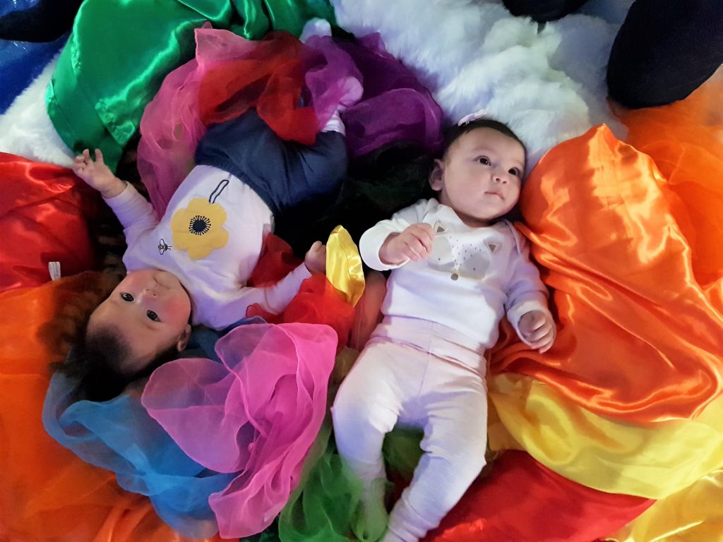 2 babies lying on colourful silk during a Baby Sensory Class in Melville